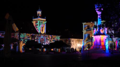 a building with a tower and a building with lights at Maksimilian Osijek in Osijek