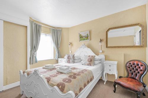 a bedroom with a bed with a mirror and a chair at Summerlands Guest House in Torquay
