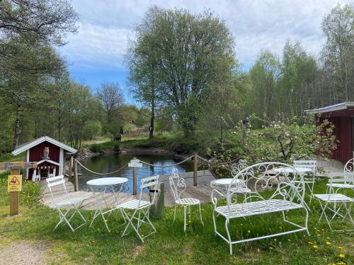 a group of chairs and tables next to a pond at Stor lägenhet ovanpå café ute på landet in Hökerum