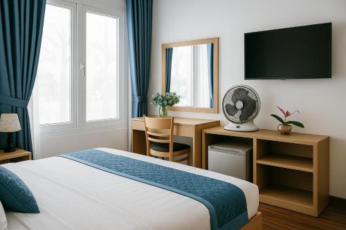 a hotel room with a bed and a desk and a tv at Tuan Thuy Hotel in Da Lat