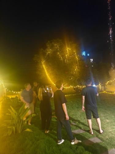 a group of people standing in the grass at night at THAT MAY Hotel in Yangshuo