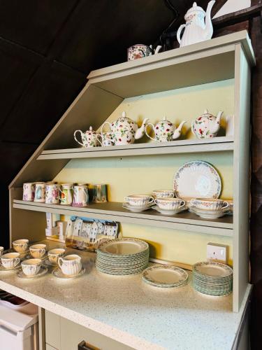 a shelf full of dishes and cups and plates at Pentre Cerrig Country House in Llanferres