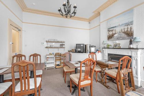 a dining room with a table and chairs and a fireplace at Summerlands Guest House in Torquay