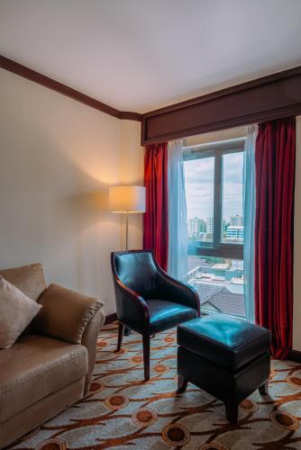 a living room with a couch and a chair and a window at Mövenpick Hotel & Residences Nairobi in Nairobi