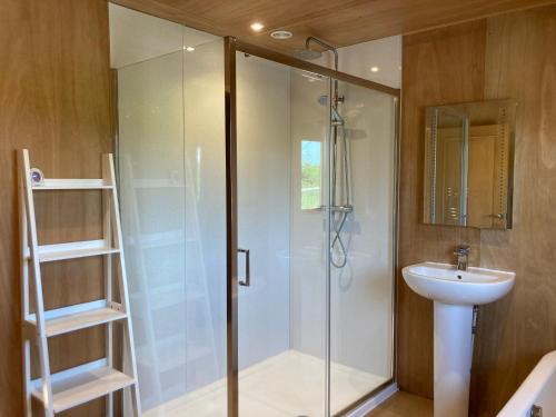 a bathroom with a glass shower and a sink at Santa's Lodge at The Cotswold Reindeer Herd in Ampney Crucis