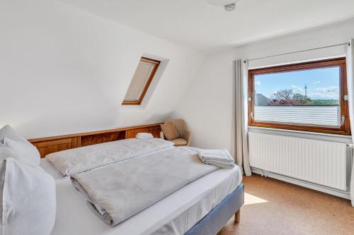 a white bedroom with a bed and a window at Wackerballig 25 in Gelting