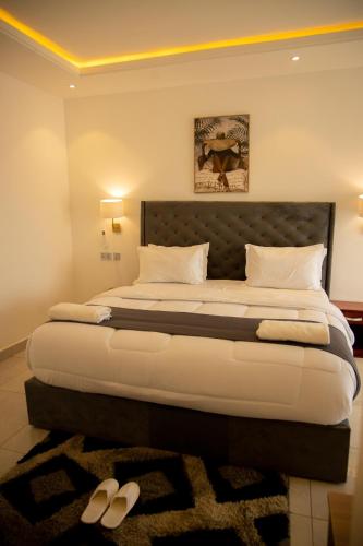 a bedroom with a large bed with two shoes on the floor at AIDEN HOMES AND APARTMENTS HOTEl in Koforidua