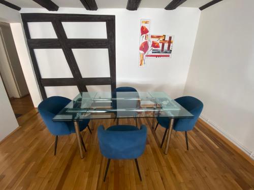 une table en verre et des chaises bleues dans une pièce dans l'établissement Appartement spacieux - cœur historique de la ville, à Barr