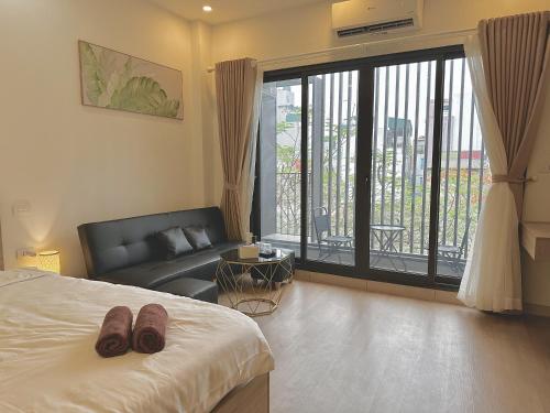 a bedroom with a bed and a couch and a window at Happy Home - Big Balcony - Best Location in Hanoi