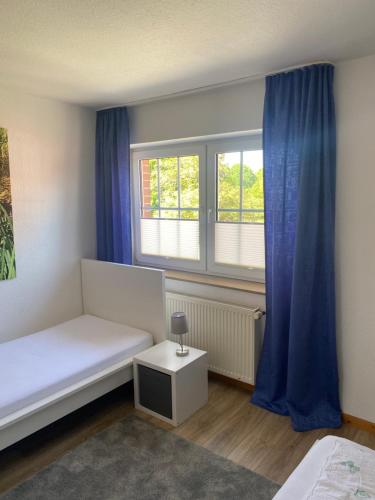 a room with a bed and two windows with blue curtains at Ferienhof Kröger in Bielefeld