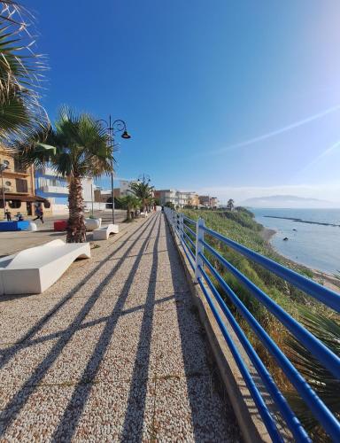 a blue fence next to a beach with palm trees at La Praiola in Trappeto