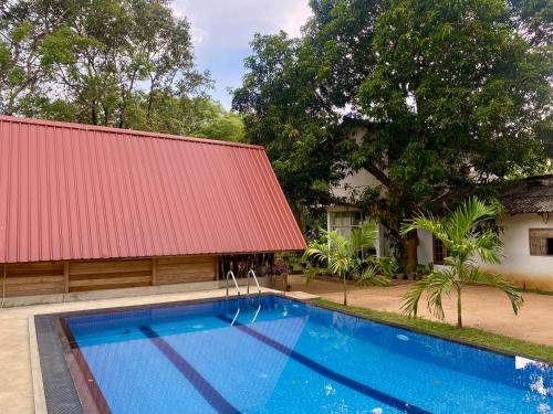 a swimming pool in front of a house with a red roof at Habarana New Star Homestay in Habarana