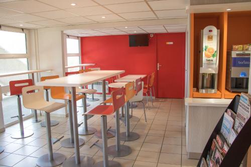 un restaurante con mesas y sillas y una pared roja en Premiere Classe Nantes Est St Sebastien Sur Loire en Saint-Sébastien-sur-Loire