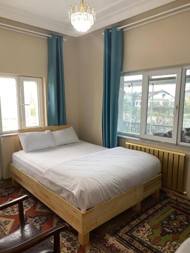 a bedroom with a bed with blue curtains and a chandelier at Hibe Dede Konak in Ürgüp