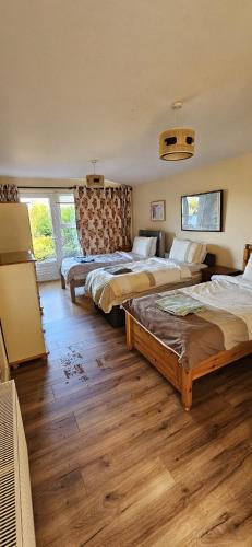 two beds in a room with wooden floors at Crossroads Portsalon in Portsalon