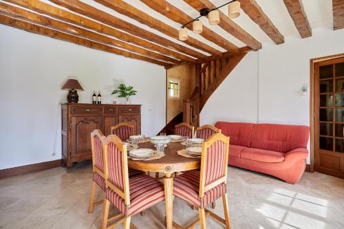 - une salle à manger avec une table et un canapé rouge dans l'établissement La Musardière - Cottage avec Grand Jardin, à Beaumont-le-Roger