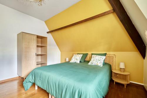- une chambre avec un lit vert et un mur jaune dans l'établissement La Musardière - Cottage avec Grand Jardin, à Beaumont-le-Roger