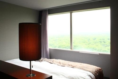 a bedroom with a bed and a large window at Hotel Epinard Nasu in Nasu