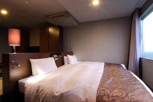 a bedroom with a bed with white sheets and a window at Hotel Epinard Nasu in Nasu