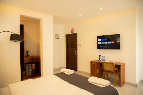 a bedroom with a bed and a desk and a television at AIDEN HOMES AND APARTMENTS HOTEl in Koforidua