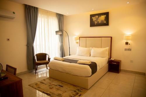 a hotel room with a bed and a chair at AIDEN HOMES AND APARTMENTS HOTEl in Koforidua