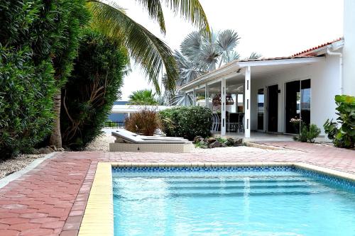 a swimming pool in front of a house at Tropical villa Curoyal near the beach in Jan Thiel