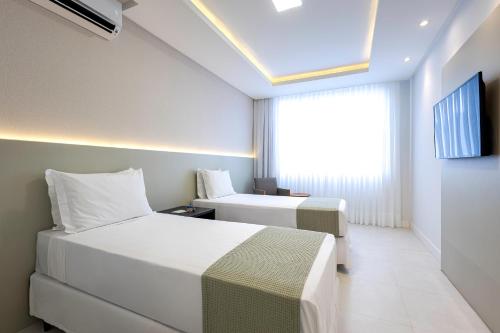 a hotel room with two beds and a window at Resort Ecoar in Gaspar