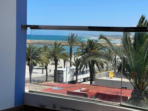 a view of a beach from a window with palm trees at PUERTO MARINA ASILAH in Asilah