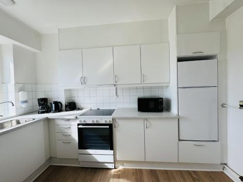 a white kitchen with white cabinets and appliances at aday - Lodsejervej Suite 4 in Randers