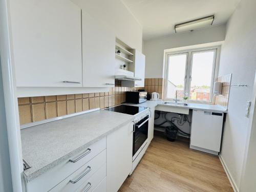 a white kitchen with white cabinets and a sink at aday - Lodsejervej Suite 1 in Randers