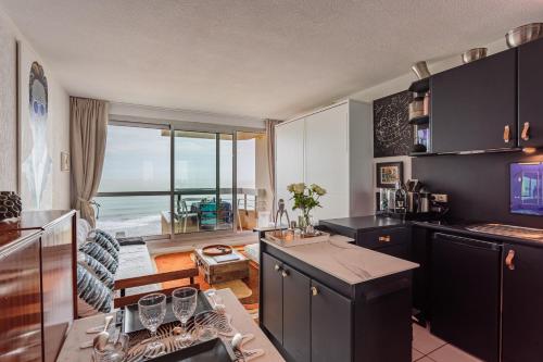 - une cuisine avec des armoires noires et une vue sur l'océan dans l'établissement Studio les pieds dans l'eau à Biarritz, à Biarritz