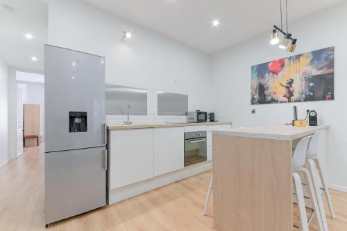 une cuisine avec des armoires blanches et un réfrigérateur blanc dans l'établissement GuestReady - Old Lyon Retreat Steps from the Metro, à Lyon