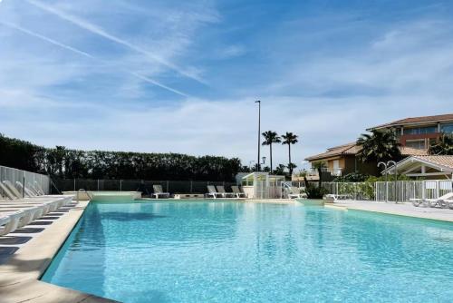 une grande piscine avec de l'eau bleue et des chaises dans l'établissement Lumineux F2 avec terrasse & piscine, Fréjus-Port, à Fréjus