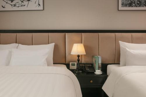a hotel room with two beds and a table with a lamp at Paradise Grand Center Hanoi Hotel in Hanoi