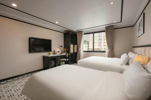 a hotel room with two beds and a television at Paradise Grand Center Hanoi Hotel in Hanoi