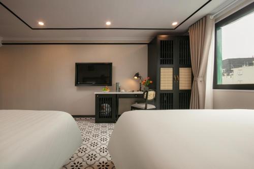 a hotel room with two beds and a television at Paradise Grand Center Hanoi Hotel in Hanoi