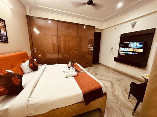 a bedroom with a large bed and a flat screen tv at JPM Suites Noida 70 in Noida
