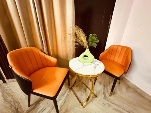 two orange chairs and a table with a vase on it at JPM Suites Noida 70 in Noida