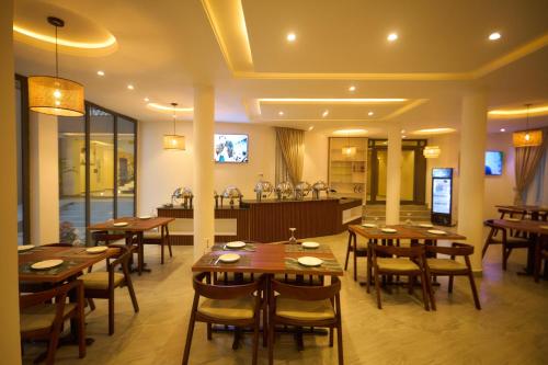 a dining room with wooden tables and a kitchen at AIDEN HOMES AND APARTMENTS HOTEl in Koforidua