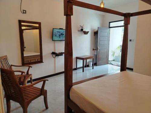 a bedroom with a bed and a mirror and a chair at Diora Hotel in Ratnapura