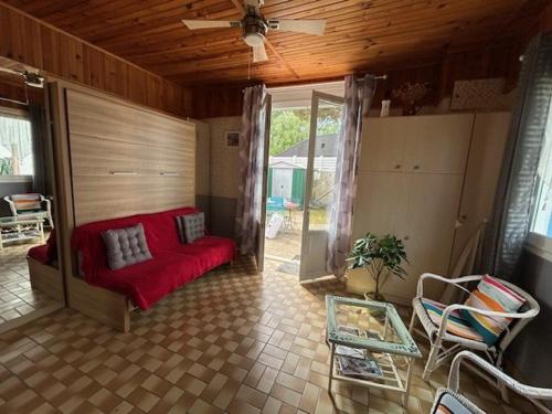 - un salon avec un canapé rouge et un ventilateur de plafond dans l'établissement Maison calme avec jardinet, proche plage et Parc de Royan - FR-1-494-56, à Royan
