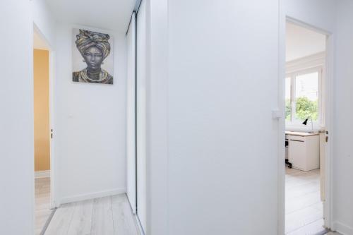 un couloir avec des murs blancs et une peinture murale dans l'établissement Meublé 3 chambres près Saint Jacques, à Clermont-Ferrand
