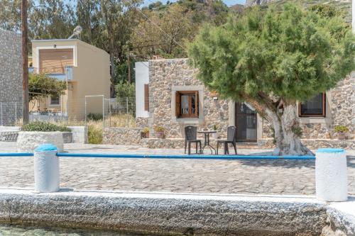 a house with a tree and a table and chairs at Peter's Paradise in Telendos