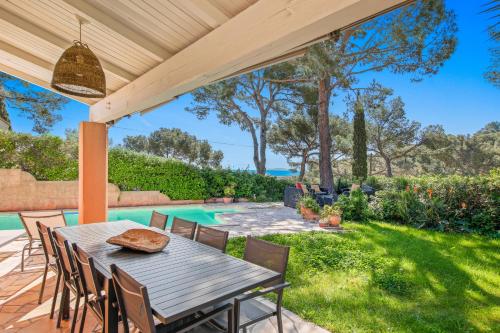 a patio with a table and chairs and a swimming pool at Vue Mer I Calme I Verdoyant I 8 Pers I Clim I BBQ in Hyères