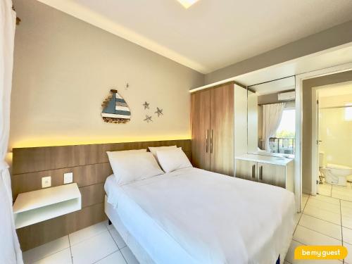 a bedroom with a white bed and a bathroom at Beach Living Pé na Areia por Be My Guest in Aquiraz