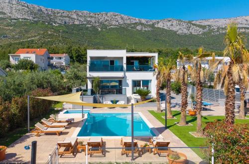 a villa with a swimming pool and mountains in the background at Seaview Villa Stanka with Pool and attached Jacuzzi in Kaštela