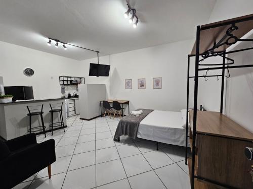 a bedroom with a bed and a kitchen with a table at Edifício Herminio Muzzi Filho in Timóteo