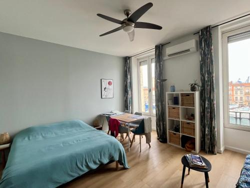 une chambre avec un lit, un bureau et un ventilateur de plafond dans l'établissement Studio climatisé - Vue canal Royal, à Sète