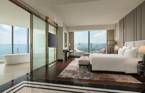 a bedroom with a white bed and a bathroom with a tub at Radisson Blu Ha Long Bay in Ha Long