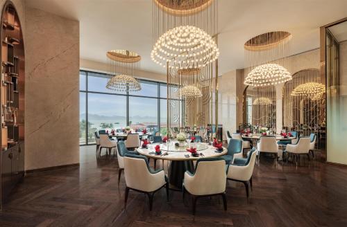 a dining room with tables and chairs and chandeliers at Radisson Blu Ha Long Bay in Ha Long